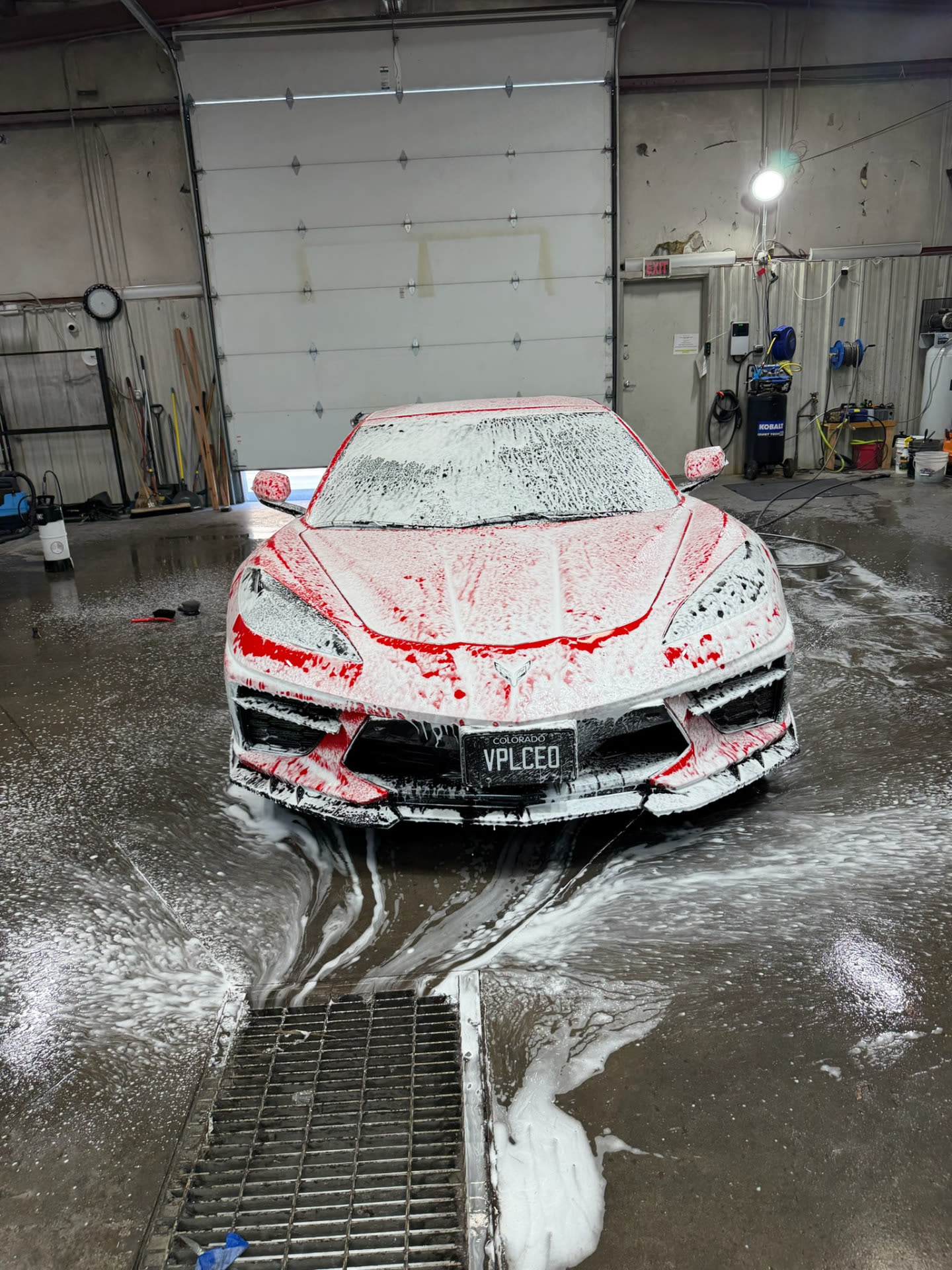 Red Corvette covered in snow foam during an exterior detail