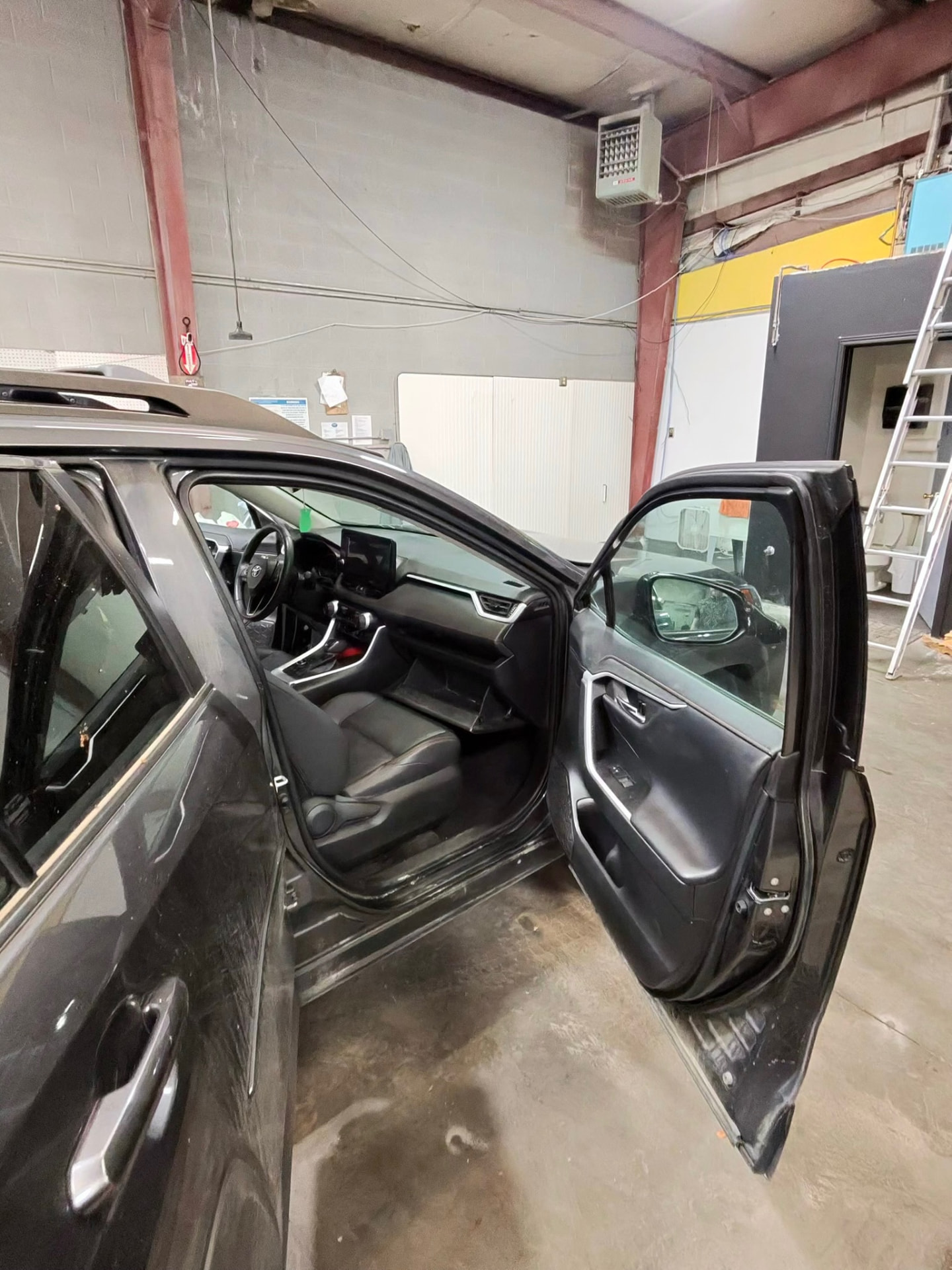 Front cabin and dash of a detailed SUV with doors open in the shop