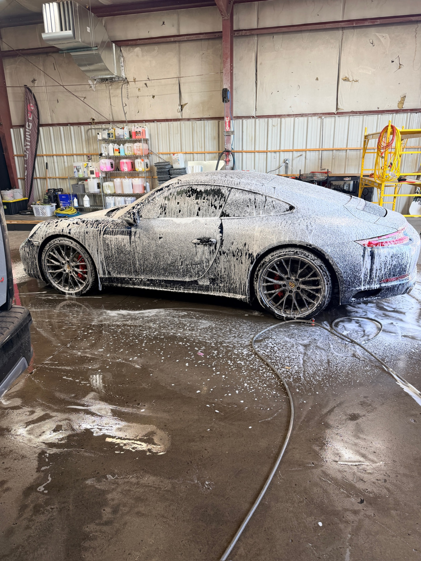 Porsche 911 covered in snow foam during the wash stage of a detail