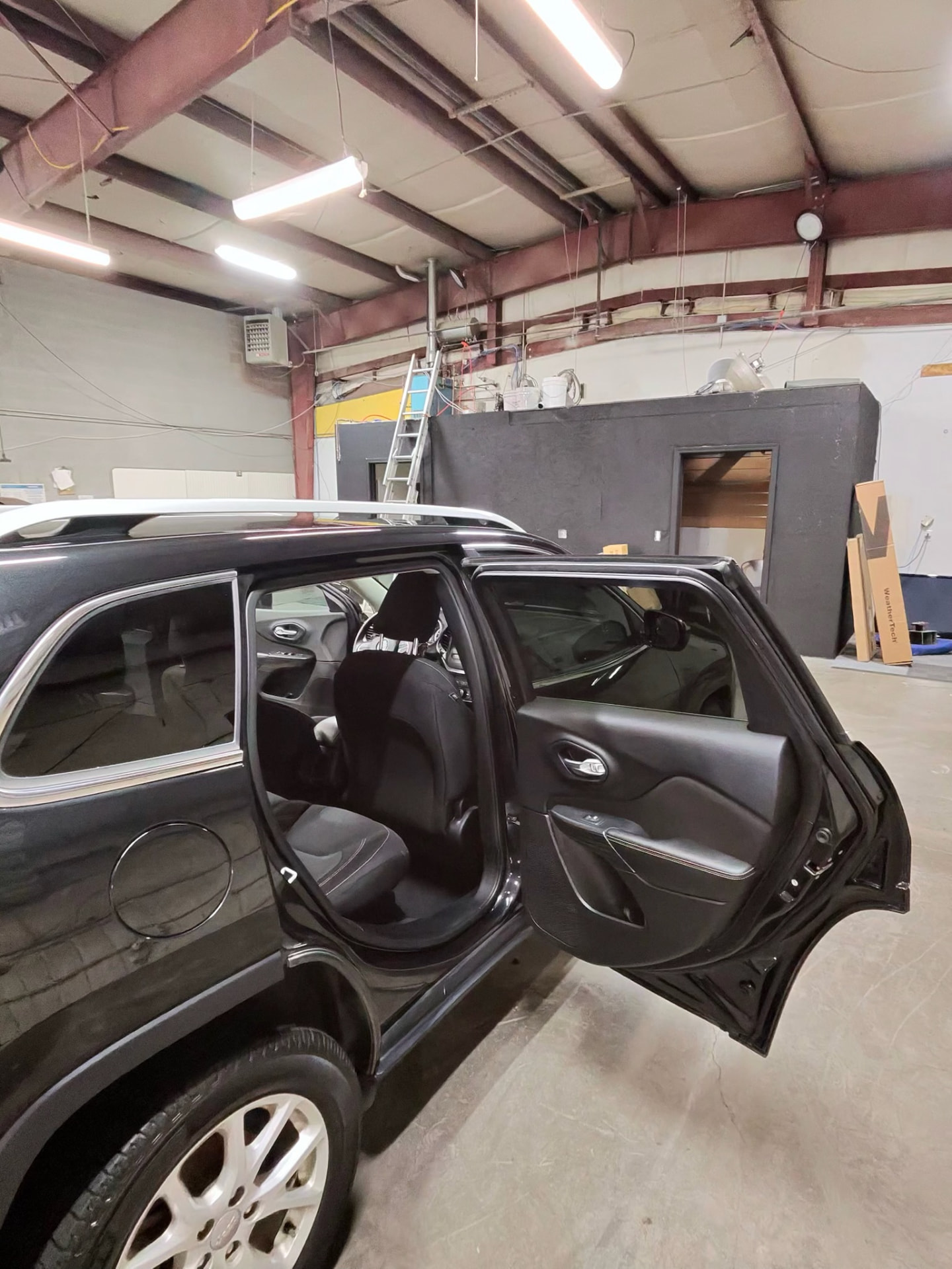 Rear door and cabin of a black Jeep Cherokee after an interior detail