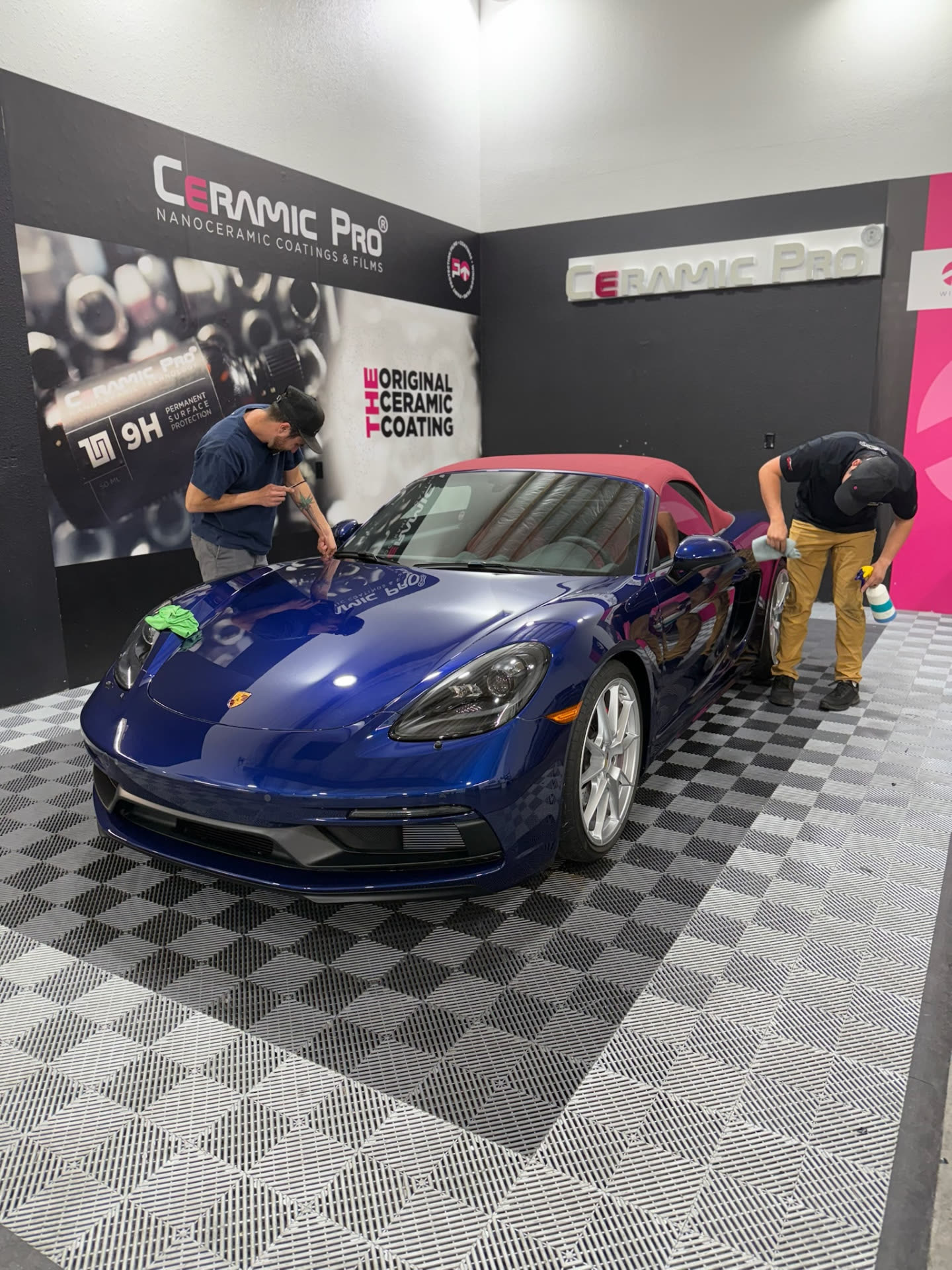 Technicians hand-finishing a blue Porsche inside the Ceramic Pro bay